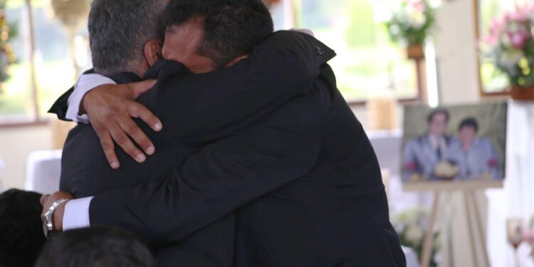 Fotografía cedida por la Unidad de Búsqueda de Personas dadas por Desaparecidas que muestra a familiares de Carmenza Castañeda de Angulo mientras se abrazan en la ceremonia de entrega de sus restos.