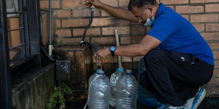 Un hombre recolecta agua potable en unos recipientes, el 12 de agosto de 2022, en Caracas (Venezuela). EFE
