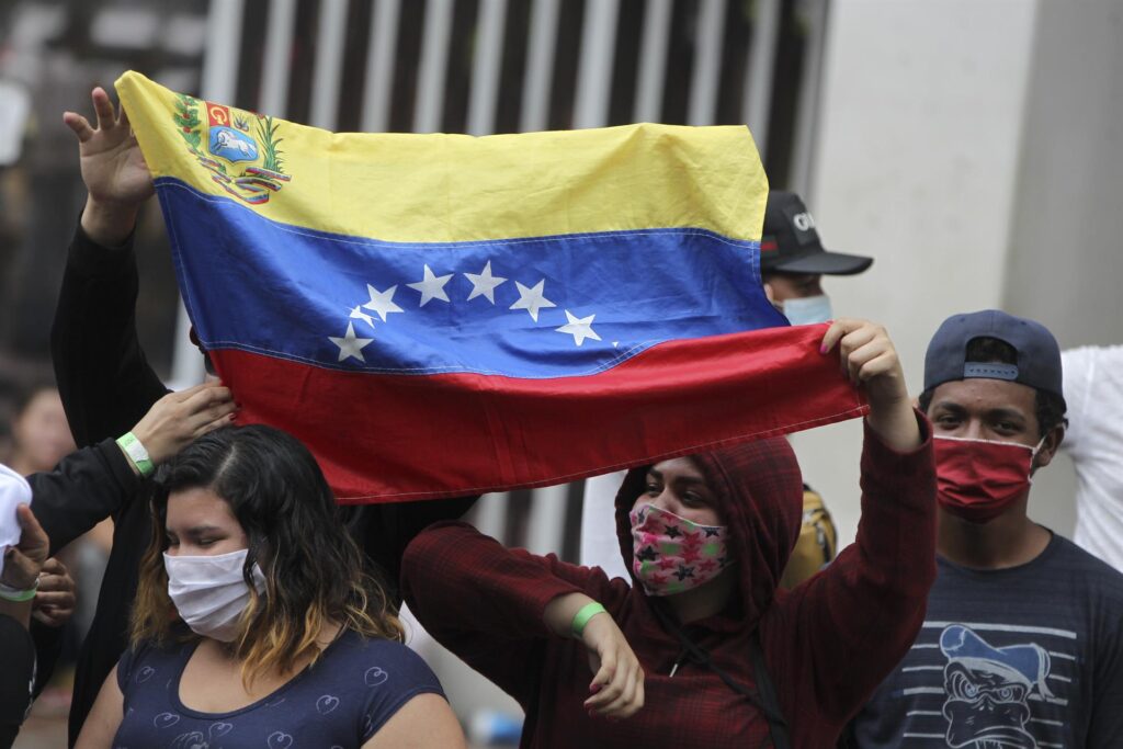Migrantes venezolanos llevan una bandera de su país, en una fotografía de archivo. EFE