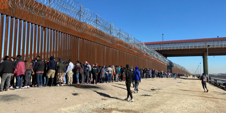 Migrantes mientras hacen fila para entregarse a la Patrulla Fronteriza estadounidense hoy, en la valla fronteriza de El Paso, Texas, frente a Ciudad Juárez, México. EFE/Octavio Guzmán
