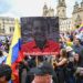 An opposer of Colombian President Gustavo Petro holds a banner with an image combining half of the faces of late Venezuelan President Hugo Chavez (L) and Petro, reading "Petro is Chavez" during a demonstration against government reforms in Bogota, on February 15, 2023. (Photo by JUAN BARRETO / AFP)