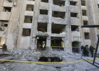 Miembros de las fuerzas de seguridad sirias se reúnen frente a un edificio dañado en un ataque con misiles israelí en Damasco, el 19 de febrero de 2023. - El Observatorio Sirio para los Derechos Humanos dijo que el ataque, que golpeó cerca de un centro cultural iraní, mató a 15 personas, incluidos los civiles. (Foto de LOUAI BESHARA / AFP)