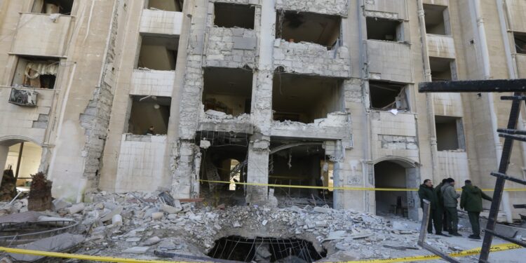 Miembros de las fuerzas de seguridad sirias se reúnen frente a un edificio dañado en un ataque con misiles israelí en Damasco, el 19 de febrero de 2023. - El Observatorio Sirio para los Derechos Humanos dijo que el ataque, que golpeó cerca de un centro cultural iraní, mató a 15 personas, incluidos los civiles. (Foto de LOUAI BESHARA / AFP)