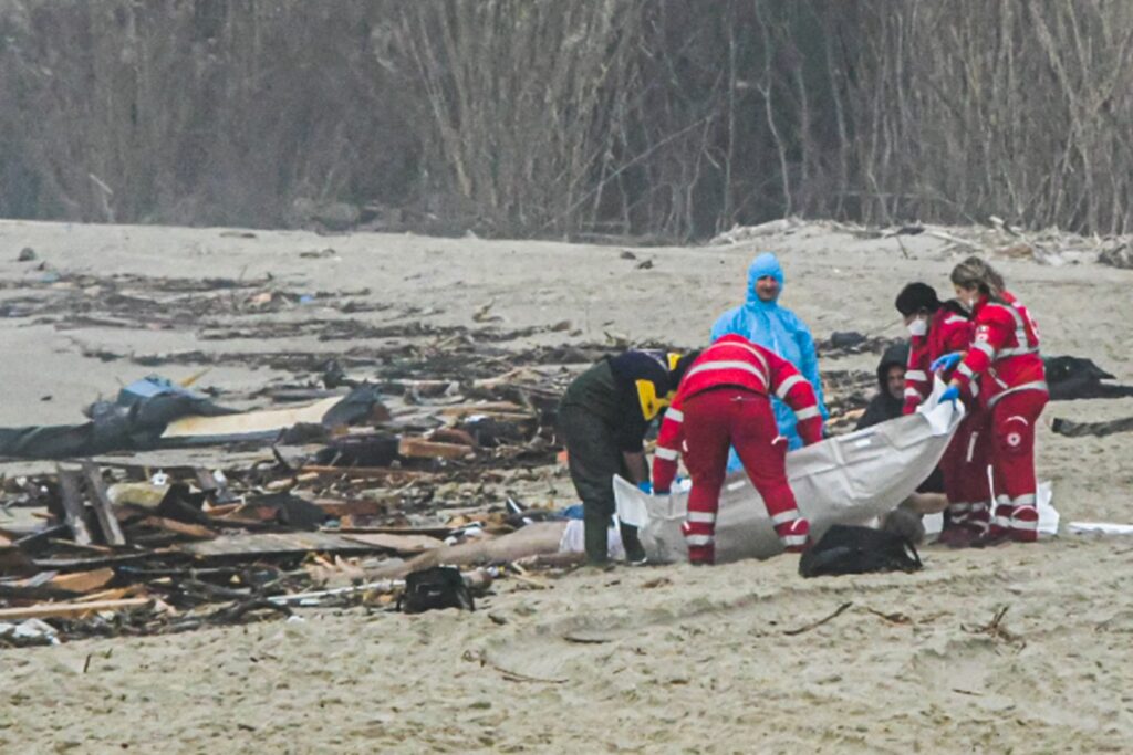 Esta foto obtenida de la agencia de noticias italiana Ansa, tomada el 26 de febrero de 2023, muestra a los rescatistas manejando una bolsa para cadáveres en el lugar de un naufragio en Steccato di Cutro, al sur de Crotone, después de que un bote de inmigrantes se hundiera frente a la región de Calabria, en el sur de Italia.