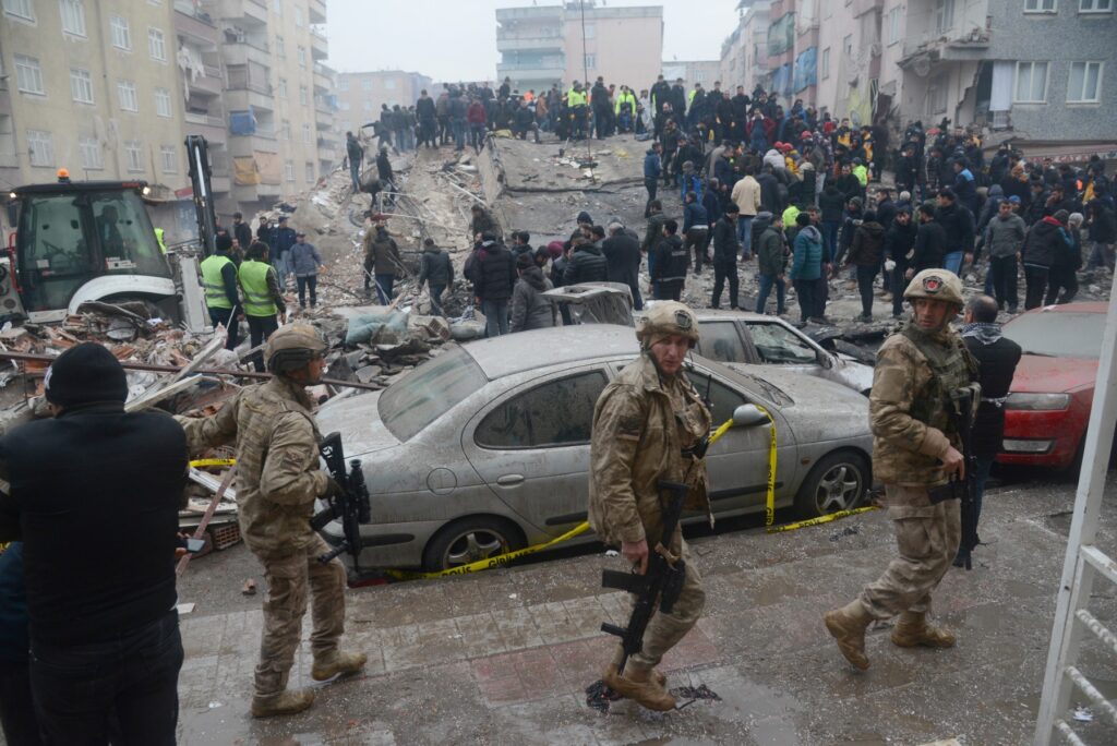 Soldados caminan mientras la gente busca sobrevivientes entre los escombros en Diyarbakir, el 6 de febrero de 2023, después de que un terremoto de magnitud 7,8 sacudiera el sureste del país. - Al menos 284 personas murieron en Turquía y más de 2300 personas resultaron heridas en uno de los terremotos más grandes de Turquía en al menos un siglo, mientras continúan los trabajos de búsqueda y rescate en varias ciudades importantes. (Foto de ILYAS AKENGIN / AFP)