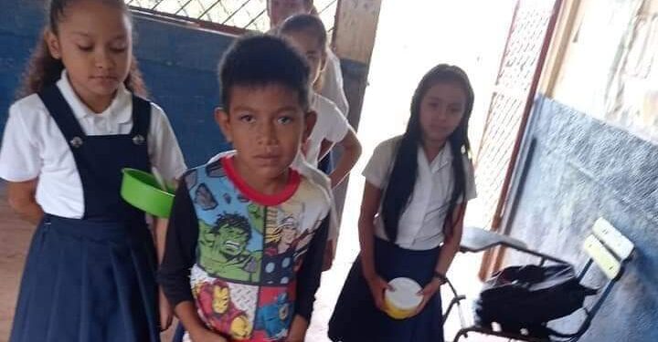 Gamaliel tomando la merienda escolar junto a otros menores, en un colegio público.