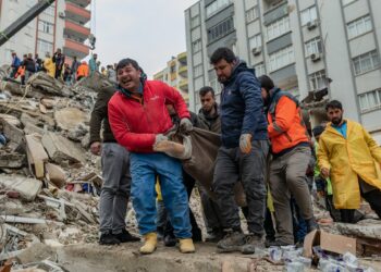 Rescuers carry a body found in the rubble in Adana on February 6, 2023, after a 7.8-magnitude earthquake struck the country's south-east. - The combined death toll has risen to over 1,900 for Turkey and Syria after the region's strongest quake in nearly a century on February 6, 2023. Turkey's emergency services said at least 1,121 people died in the 7.8-magnitude earthquake, with another 783 confirmed fatalities in Syria, putting that toll at 1,904. (Photo by Can EROK / AFP)