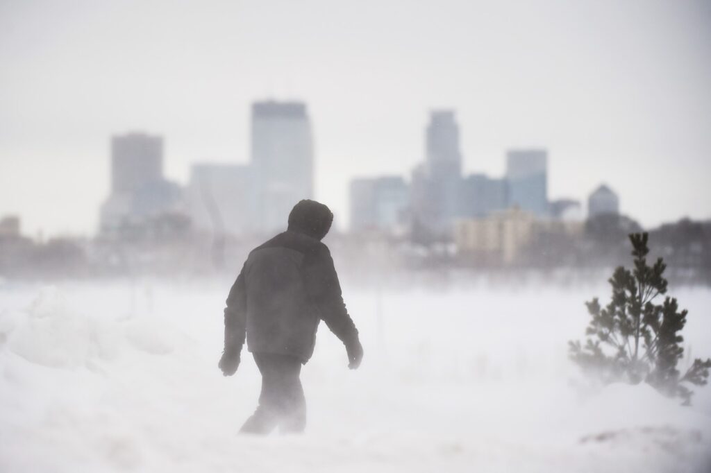 Un hombre da un paseo frente al horizonte de Minneapolis en Bde Maka Ska Park durante una tormenta de nieve en Minneapolis, Minnesota, el 22 de febrero de 2023.