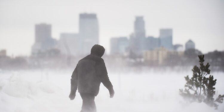 Un hombre da un paseo frente al horizonte de Minneapolis en Bde Maka Ska Park durante una tormenta de nieve en Minneapolis, Minnesota, el 22 de febrero de 2023.