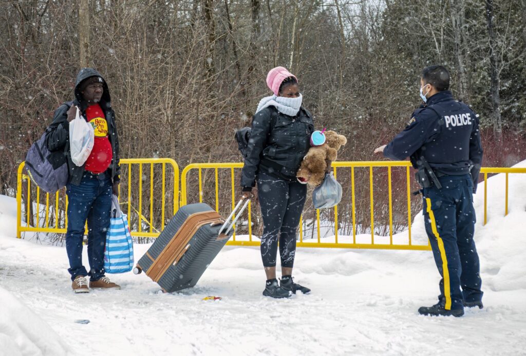 Un oficial habla con los migrantes cuando llegan al cruce fronterizo de Roxham Road en Roxham, Quebec, Canadá, el 2 de marzo de 2023. - En 2022, el número de solicitantes de asilo que cruzaron a Quebec por esta carretera superó los 39.000, duplicando el récord anterior. de 2017. (Foto de Sebastien ST-JEAN / AFP)