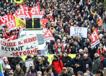 Los manifestantes sostienen pancartas y banderas durante una manifestación como parte de un día nacional de huelgas y protestas convocadas por los sindicatos por la reforma propuesta de las pensiones en Nantes, en el oeste de Francia, el 11 de marzo de 2023.