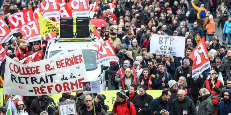 Los manifestantes sostienen pancartas y banderas durante una manifestación como parte de un día nacional de huelgas y protestas convocadas por los sindicatos por la reforma propuesta de las pensiones en Nantes, en el oeste de Francia, el 11 de marzo de 2023.