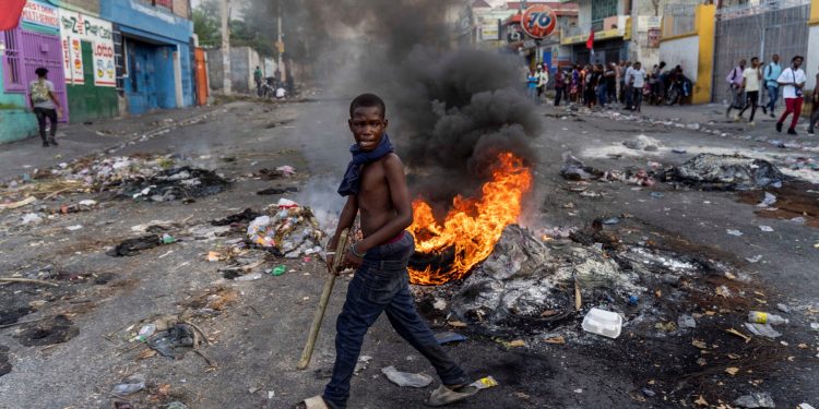 A mans walks past a burning barricade during a protest against Haitian Prime Minister Ariel Henry calling for his resignation, in Port-au-Prince, Haiti, October 10, 2022. - Protests and looting have rocked the already unstable country since September 11, when Prime Minister Ariel Henry announced a fuel price hike. (Photo by Richard Pierrin / AFP)