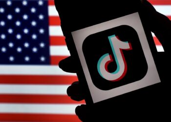 En esta ilustración de fotografía de archivo tomada el 3 de agosto de 2020, el logotipo de la aplicación de redes sociales, TikTok, se muestra en la pantalla de un iPhone sobre un fondo de bandera de EE. UU. en Arlington, Virginia.