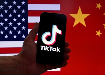 Esta ilustración fotográfica de archivo tomada el 16 de marzo de 2023 muestra el logotipo de TikTok en la pantalla de un iPhone frente a una bandera de EE. UU. y China en Washington, DC. - Beijing dijo el 24 de marzo de 2023 que no pide a las empresas que entreguen los datos recopilados en el extranjero, ya que TikTok, de propiedad china, enfrenta una presión cada vez mayor y pide una prohibición en los Estados Unidos. (Foto de OLIVIER DOULIERY / AFP)