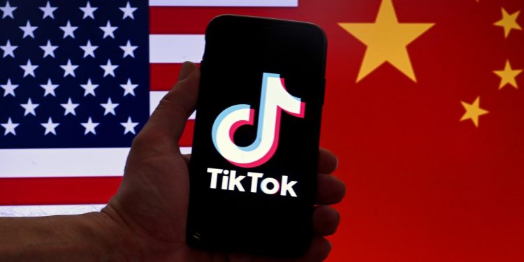 Esta ilustración fotográfica de archivo tomada el 16 de marzo de 2023 muestra el logotipo de TikTok en la pantalla de un iPhone frente a una bandera de EE. UU. y China en Washington, DC. - Beijing dijo el 24 de marzo de 2023 que no pide a las empresas que entreguen los datos recopilados en el extranjero, ya que TikTok, de propiedad china, enfrenta una presión cada vez mayor y pide una prohibición en los Estados Unidos. (Foto de OLIVIER DOULIERY / AFP)