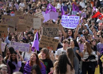 Una mujer sostiene una pancarta que dice "A mí también me gustan las mujeres pero no las acoso" durante una manifestación de estudiantes con motivo del Día Internacional de la Mujer en Barcelona el 8 de marzo de 2023. (Foto de LLUIS GENE / AFP)