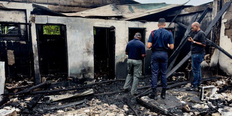Investigadores y empleados del gobierno inspeccionan el dormitorio de la escuela donde un incendio mató al menos a 19 personas en Mahdia, Guyana el 22 de mayo de 2023. - Al menos 19 personas, la mayoría jóvenes, murieron y varios resultaron heridos el domingo en un incendio en un dormitorio de una escuela en Guyana , dijo el gobierno en un comunicado, y el presidente de la nación lo calificó como un "gran desastre". (Foto de Keno GEORGE / AFP)