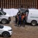 Migrantes abordan un vehículo para ser procesados por las autoridades estadounidenses en el lado estadounidense de la frontera entre Estados Unidos y México, visto desde Tijuana, estado de Baja California, México, el 11 de mayo de 2023.