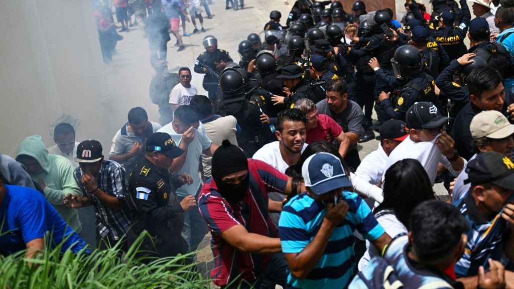 Votantes que protestan chocan con agentes de policía frente a un centro de votación que permanece cerrado tras presuntas amenazas e irregularidades durante las elecciones generales, en San José del Golfo, en las afueras del norte de la Ciudad de Guatemala el 25 de junio de 2023. Residentes de dos municipios guatemaltecos se enfrentaron a agentes de policía
que lanzaron gases lacrimógenos para disolver las protestas por supuestas anomalías en las elecciones generales del domingo, dijeron las autoridades. Los hechos ocurrieron en San José del Golfo, en la periferia nororiental de la capital, donde se suspendió la votación, así como en San Martín Zapotitlán, al sur de Ciudad de Guatemala, según informó el ente electoral. (Foto por Johan ORDONEZ / AFP)