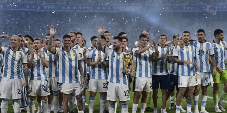 El delantero argentino Lionel Messi (C) sostiene una réplica del trofeo de la Copa del Mundo junto a sus compañeros de equipo durante una ceremonia de reconocimiento a los jugadores ganadores de la Copa del Mundo, luego del partido amistoso de fútbol entre Argentina y Curazao en el estadio Madre de Ciudades en Santiago del Estero, en el norte de Argentina, el 28 de marzo de 2023.
