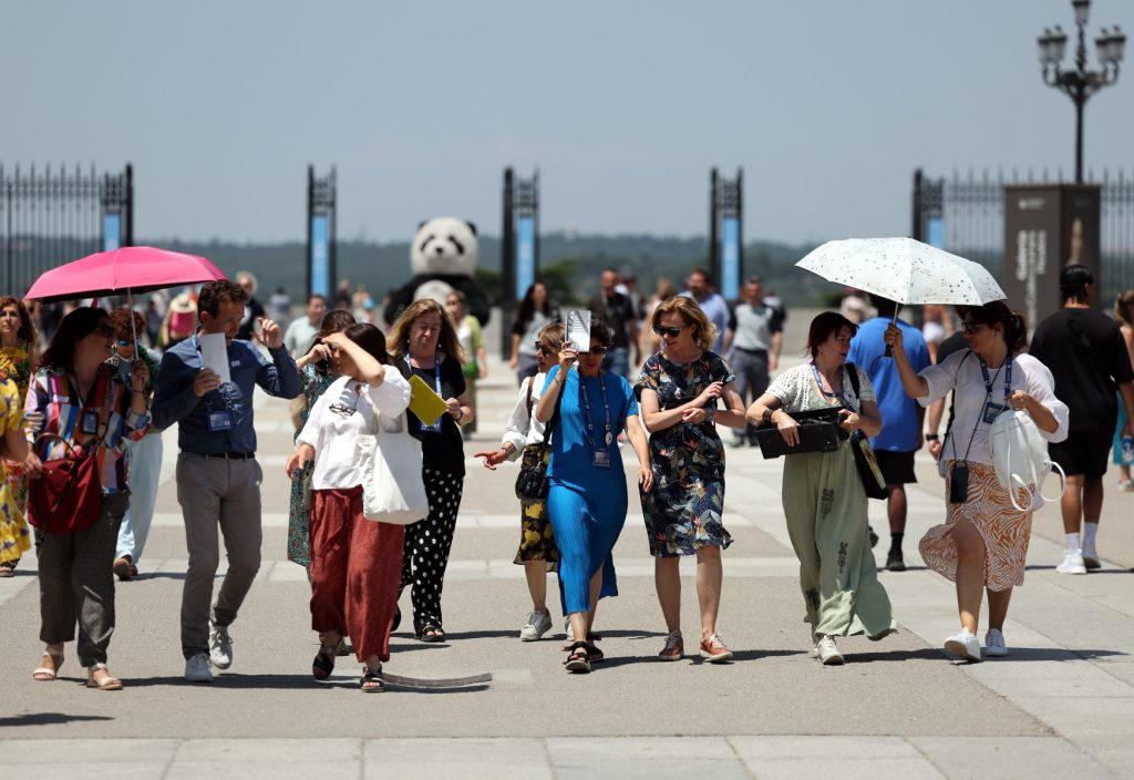 Los turistas se protegen del sol mientras visitan el Palacio Real en el centro de la ciudad de Madrid bajo temperaturas muy altas, el 26 de junio de 2023, cuando España se enfrenta a su primera ola de calor del verano, con temperaturas que se espera que superen los 44 grados localmente en el sur del país