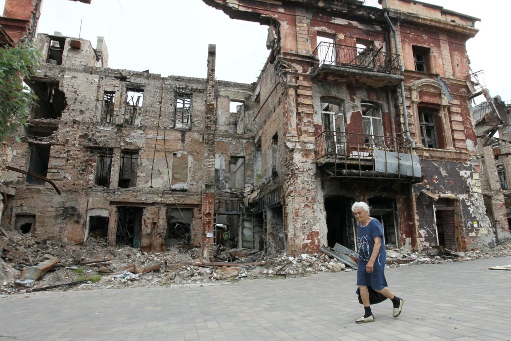 Una mujer pasa frente a un edificio destruido en la ciudad portuaria de Mariupol, en el mar de Azov, controlada por Rusia, en el sureste de Ucrania, el 10 de junio de 2023. (Foto de STRINGER / AFP)