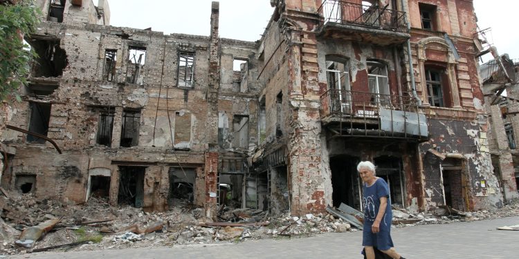 Una mujer pasa frente a un edificio destruido en la ciudad portuaria de Mariupol, en el mar de Azov, controlada por Rusia, en el sureste de Ucrania, el 10 de junio de 2023. (Foto de STRINGER / AFP)