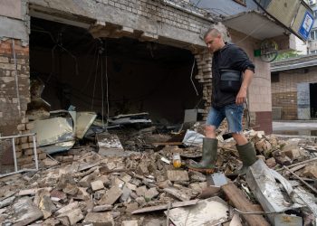 Un residente local limpia los escombros de una tienda destruida después de un bombardeo ruso en Kherson, el 12 de junio de 2023, mientras la región enfrenta inundaciones masivas por la destrucción de la represa de la central hidroeléctrica Kakhovka. (Foto de Oleksii FILIPPOV / AFP)