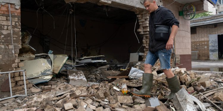 Un residente local limpia los escombros de una tienda destruida después de un bombardeo ruso en Kherson, el 12 de junio de 2023, mientras la región enfrenta inundaciones masivas por la destrucción de la represa de la central hidroeléctrica Kakhovka. (Foto de Oleksii FILIPPOV / AFP)