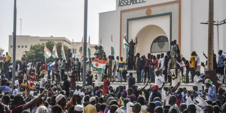Supporters wave Nigerien's flags as they rally in support of Niger's junta in front of the National Assembly in Niamey on July 30, 2023. - Niger's junta on Sunday said ECOWAS could stage an imminent military intervention in the capital Niamey as the regional body meets for an "extraordinary summit" on the coup-hit country, with sanctions a possibility. The country's elected president Mohamed Bazoum has been held by the military for four days, and General Abdourahamane Tiani, the chief of the powerful presidential guard, has declared himself leader. (Photo by - / AFP)