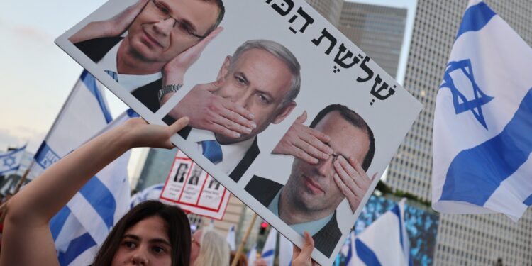 Un manifestante lleva un cartel durante una marcha en Tel Aviv el 22 de julio de 2023, parte de una marcha de varios días para protestar contra el proyecto de ley de reforma judicial del gobierno antes de una votación en el parlamento. - Israel se ha visto sacudido por una ola de protestas de meses después de que el gobierno revelara en enero planes para reformar el sistema judicial que, según los opositores, amenazan la democracia del país. (Foto de JACK GUEZ / AFP)