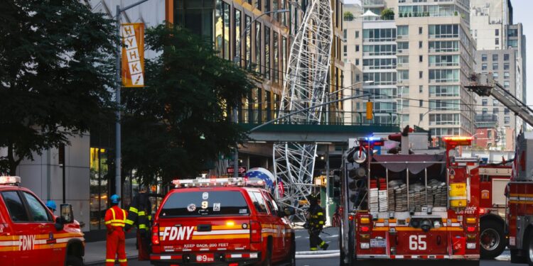 Los bomberos inspeccionan una grúa de construcción que se incendió y colapsó en Nueva York, el 26 de julio de 2023. - El Departamento de Bomberos de la ciudad de Nueva York informó que dos bomberos y al menos cuatro civiles sufrieron heridas leves en el accidente. (Foto de Kena Betancur / AFP)