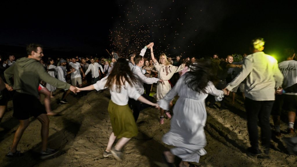 TOPSHOT - La gente baila durante las celebraciones nocturnas de Kupala cerca del pueblo de Yagidne, región de Chernigiv, el 8 de julio de 2023 después de ofrecerse como voluntario para limpiar los escombros de los edificios destruidos en la región, en medio de la invasión rusa de Ucrania. (Foto de Genya SAVILOV / AFP)