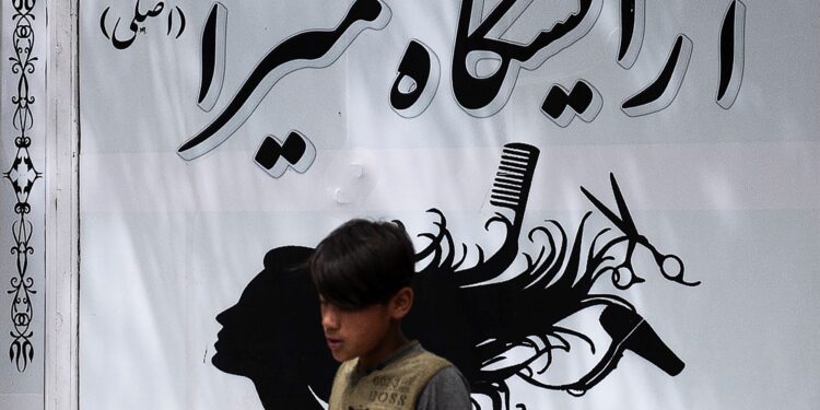 Un niño pasa frente a un salón de belleza en el área de Shahr-e Naw en Kabul el 4 de julio de 2023. - Las autoridades talibanes de Afganistán ordenaron el cierre de los salones de belleza en todo el país dentro de un mes, confirmó el viceministerio el 4 de julio, la última restricción. para sacar aún más a las mujeres de la vida pública. (Foto de Wakil KOHSAR / AFP)