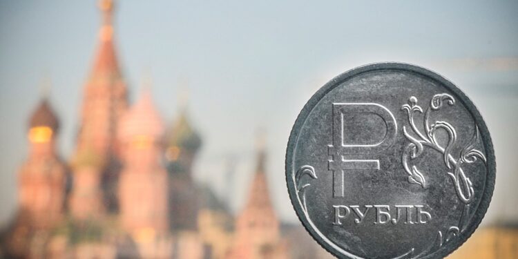 Una moneda de rublo ruso se muestra frente a la catedral de San Basilio en el centro de Moscú, el 28 de abril de 2022. - El rublo ruso se deslizó más allá de 100 frente al dólar el 14 de agosto de 2023, su nivel más bajo desde el 23 de marzo de 2022 -- poco después de que Moscú lanzara su operación militar en Ucrania. (Foto de Alexander NEMENOV / AFP)