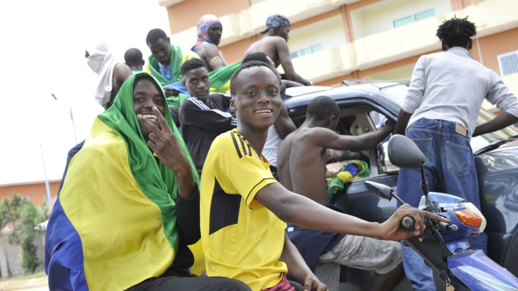Un hombre con una bandera nacional de Gabón sobre sus hombros hace un gesto mientras celebran en Libreville el 30 de agosto de 2023 después de que un grupo de oficiales militares gaboneses aparecieran en la televisión anunciando que estaban "poniendo fin al régimen actual" y descartando las elecciones oficiales. Foto: Artículo 66 / AFP
