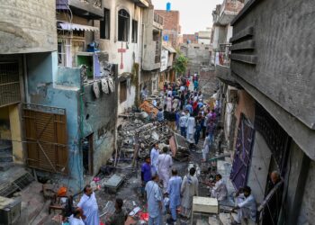 Los residentes se paran entre los escombros junto a la iglesia de San Juan incendiada en Jaranwala, en las afueras de Faisalabad, el 17 de agosto de 2023, un día después de un ataque de hombres musulmanes tras las acusaciones de que los cristianos habían profanado el Corán.