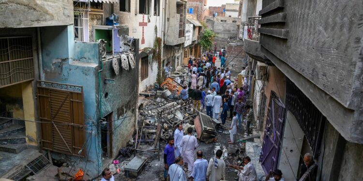 Los residentes se paran entre los escombros junto a la iglesia de San Juan incendiada en Jaranwala, en las afueras de Faisalabad, el 17 de agosto de 2023, un día después de un ataque de hombres musulmanes tras las acusaciones de que los cristianos habían profanado el Corán.