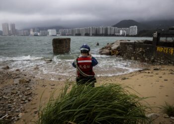 Un miembro del Servicio de Ayuda Civil (CAS) evalúa la marea creciente causada por el súper tifón Saola en una aldea de Lei Yue Mun en Hong Kong el 2 de septiembre de 2023. - El tifón Saola arrasó el sur de China el 2 de septiembre después de derribar árboles y