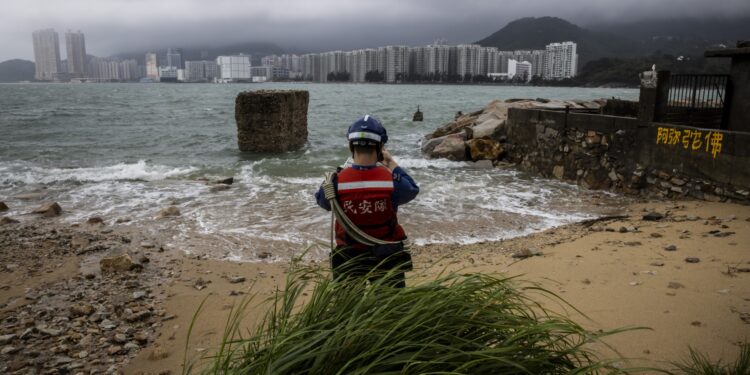 Un miembro del Servicio de Ayuda Civil (CAS) evalúa la marea creciente causada por el súper tifón Saola en una aldea de Lei Yue Mun en Hong Kong el 2 de septiembre de 2023. - El tifón Saola arrasó el sur de China el 2 de septiembre después de derribar árboles y
