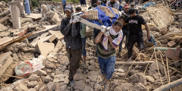 People carry the remains of a victim of the deadly 6.8-magnitude September 8 earthquake, in the village of Imi N'Tala near Amizmiz in central Morocco on September 10, 2023. - Using heavy equipment and even their bare hands, rescuers in Morocco on September 10 stepped up efforts to find survivors of a devastating earthquake that killed more than 2,100 people and flattened villages. (Photo by FADEL SENNA / AFP)