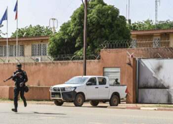 Un oficial de la Policía Nacional de Níger cruza la calle frente a la Embajada de Francia en Niamey el 28 de agosto de 2023. - El presidente francés, Emmanuel Macron, anunció el 24 de septiembre de 2023 que Francia retiraría a su embajador de Níger, seguido de el contingente militar francés en los próximos meses, una medida bienvenida por los líderes militares de Níger como un "paso hacia la soberanía". (Foto de AFP)