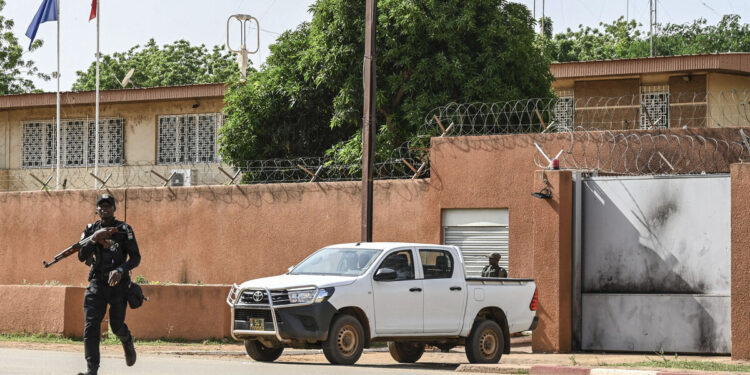 Un oficial de la Policía Nacional de Níger cruza la calle frente a la Embajada de Francia en Niamey el 28 de agosto de 2023. - El presidente francés, Emmanuel Macron, anunció el 24 de septiembre de 2023 que Francia retiraría a su embajador de Níger, seguido de el contingente militar francés en los próximos meses, una medida bienvenida por los líderes militares de Níger como un "paso hacia la soberanía". (Foto de AFP)