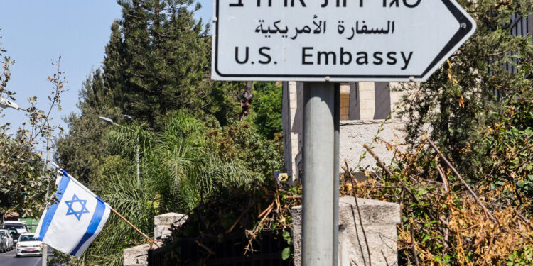 Una bandera israelí se exhibe frente a un edificio cerca de una señal de tráfico de la embajada de Estados Unidos en Jerusalén el 27 de septiembre de 2023. - Estados Unidos dijo el 27 de septiembre que comenzaría a permitir visitas de israelíes sin visas, después de lo que dijo fueron esfuerzos exitosos. por su aliado para abordar las preocupaciones de que discrimina a los árabes estadounidenses, una evaluación cuestionada por algunos legisladores. (Foto de Ahmad GHARABLI / AFP)