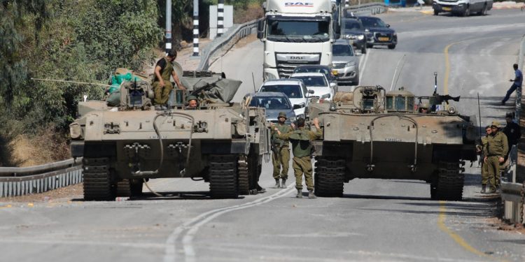 Soldados israelíes en vehículos blindados conducen por una calle cerca de la ciudad norteña de Kiryat Shmona, cerca de la frontera con el Líbano, el 13 de octubre de 2023. - Israel bombardeó una región fronteriza en el sur del Líbano, dijeron dos fuentes de seguridad libanesas, después de que se produjera una explosión en la valla fronteriza, según el ejército israelí. (Foto de Jalaa MAREY / AFP)