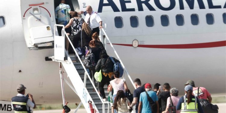 La gente aborda un avión después del paso del huracán Otis en el Aeropuerto Internacional de Acapulco en Acapulco, México, el 27 de octubre de 2023. - Las aerolíneas comenzaron a evacuar a turistas de la ciudad costera mexicana de Acapulco el viernes después de que un huracán de categoría 5 de gran escala dejara un rastro