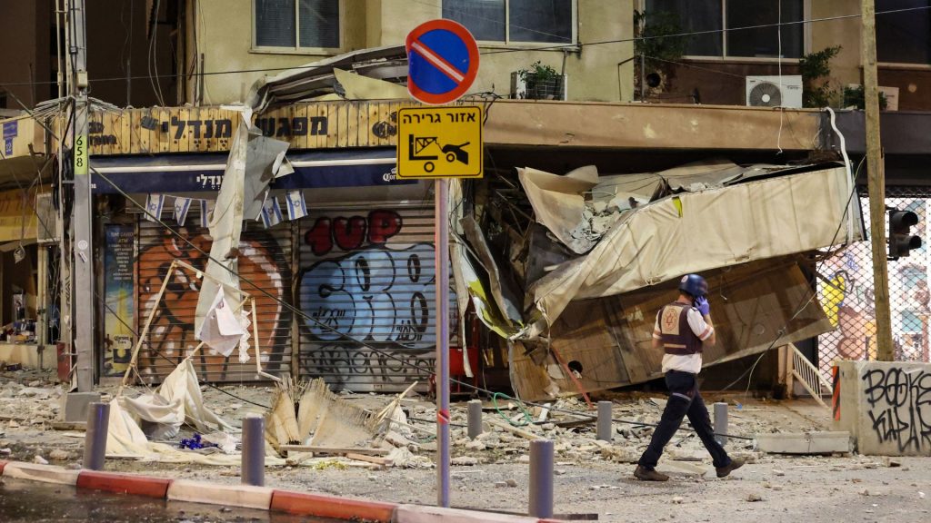 n rescatista israelí camina frente a una tienda dañada en Tel Aviv, después de que fuera alcanzada por un cohete disparado por militantes palestinos desde la Franja de Gaza, este sábado, siete de octubre. Foto: Artículo 66 / AFP