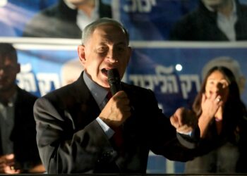 El líder del partido Likud de Israel y ex primer ministro, Benjamin Netanyahu, habla con sus partidarios detrás de una pantalla de seguridad durante un mitin de campaña junto a su esposa Sara (no en la foto) y la miembro del Likud Miri Regev (R) en la ciudad norteña de Tirat Carmel el 25 de octubre de 2022. , de cara a las elecciones generales de noviembre. (Foto de GIL COHEN-MAGEN / AFP)