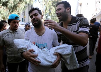 NOTA DEL EDITOR: Contenido gráfico / Un palestino sostiene el cuerpo de un niño envuelto en una mortaja mientras otro reacciona junto a él, afuera de un hospital luego del bombardeo israelí del suburbio oriental de Shujaiya en la ciudad de Gaza el 4 de noviembre de 2023, en medio de las batallas en curso entre Israel. y el grupo palestino Hamás. - Los combates estallaron en Gaza el 4 de noviembre, día 29 desde que militantes de Hamás irrumpieron en la frontera israelí y, según funcionarios israelíes, mataron a 1.400 personas, en su mayoría civiles, y secuestraron a más de 240 personas más. Desde entonces, Israel ha bombardeado implacablemente la Franja de Gaza y ha enviado tropas terrestres, y el Ministerio de Salud en el territorio palestino gobernado por Hamás dice que 9.488 personas han muerto, alrededor de dos tercios de ellas mujeres y niños. (Foto de Dawood NEMER / AFP)